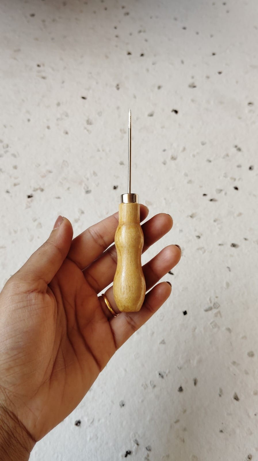 Single wooden-handled bookbinding awl held in hand showing tapered steel point