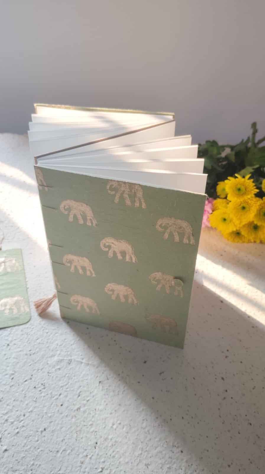 Olive-green buttonhole-bound journal with block-printed elephant motif cover, standing open