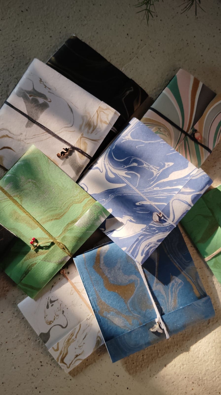 Flatlay of hand-bound Coptic journals with marbled covers in indigo, teal, and cream