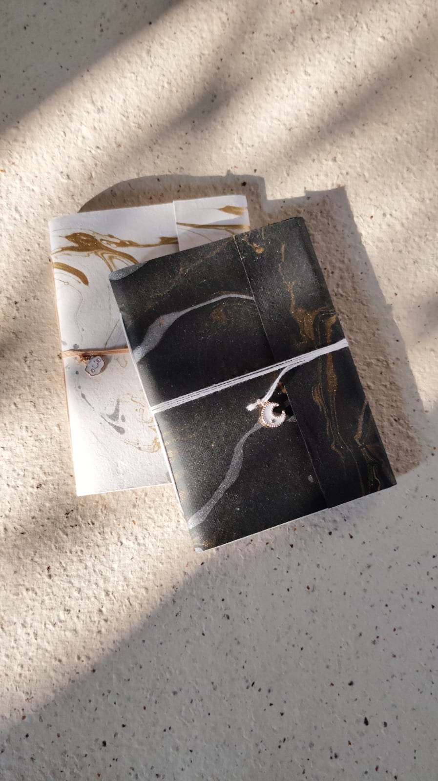 Pair of marbled-cover Coptic journals — black-and-gold and white-and-gold marble patterns