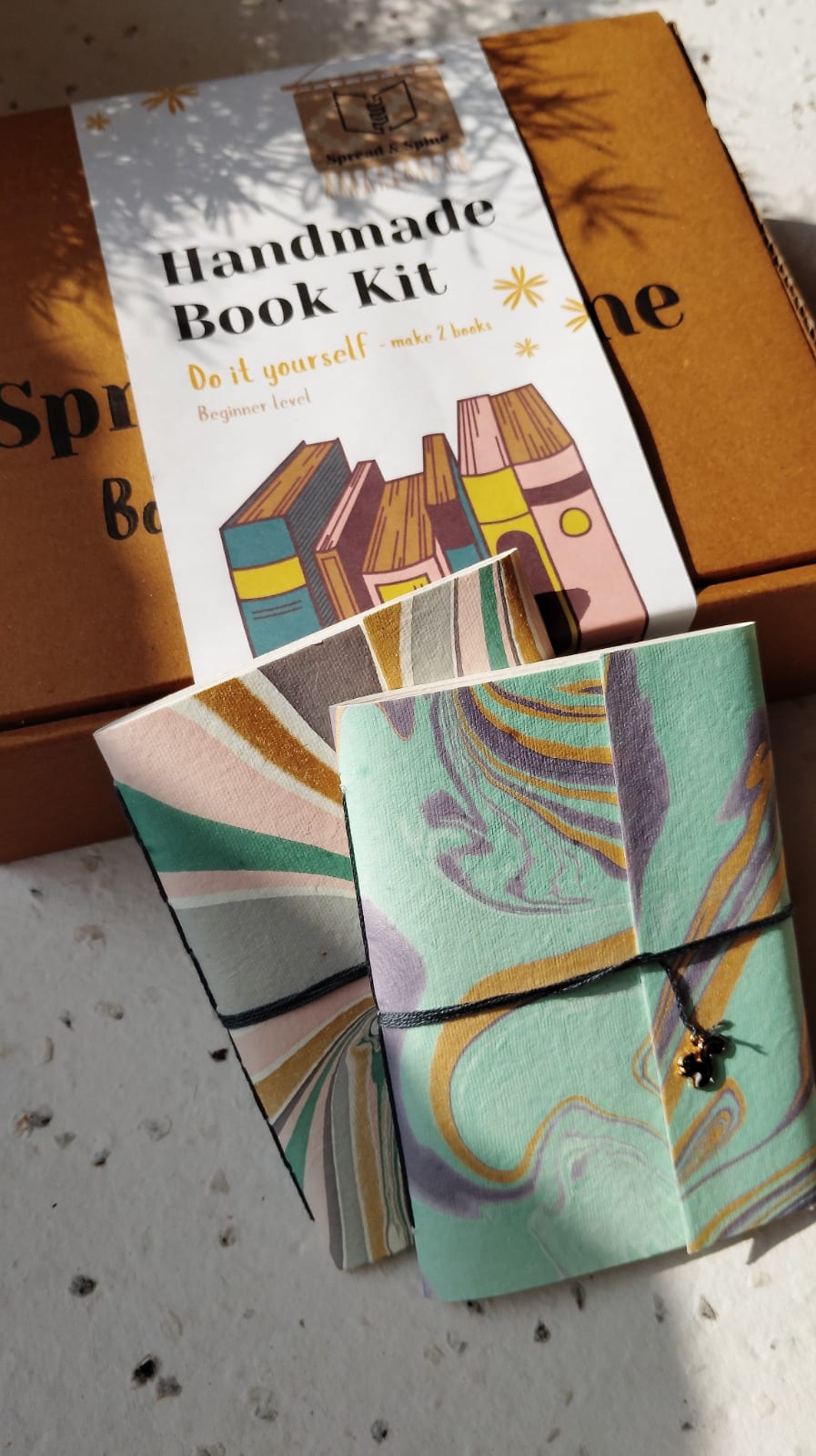 Two marbled journals made from the Handmade Book Kit, resting on the kit box