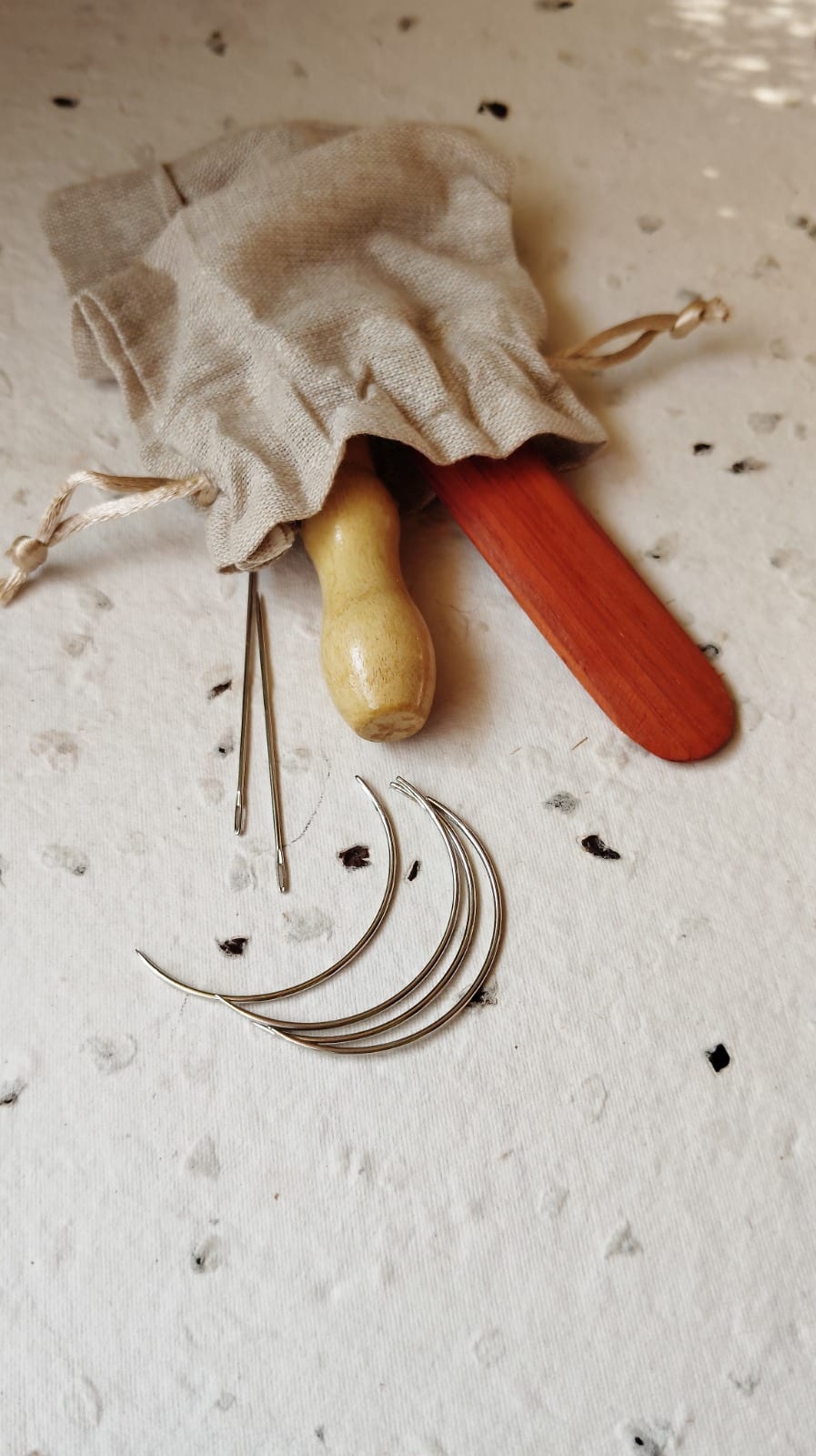 Kit contents — bookbinding needles, awl and bone folder packed in a linen drawstring pouch