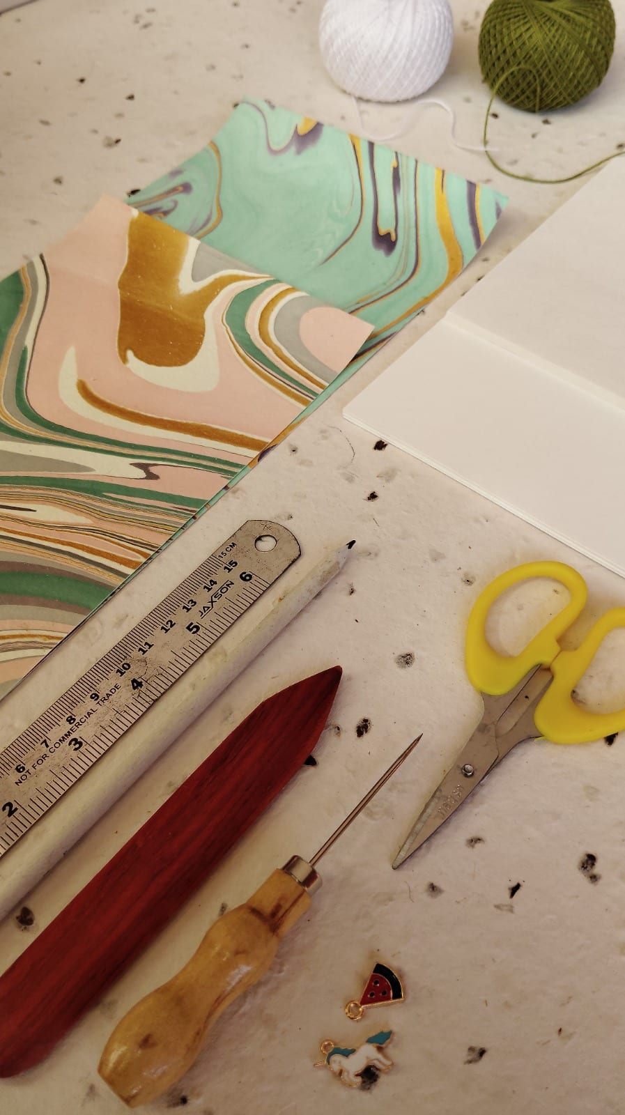 Hand-marbled A5 endpaper pair in teal and ochre, styled with bookbinding tools