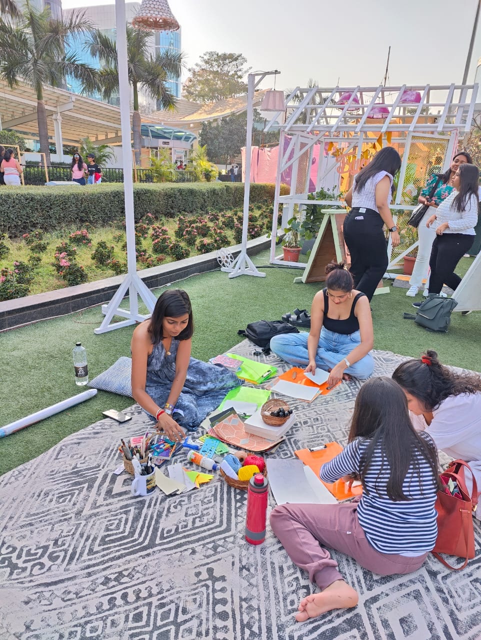Corporate team-building bookbinding session on an outdoor mat at a Bengaluru venue